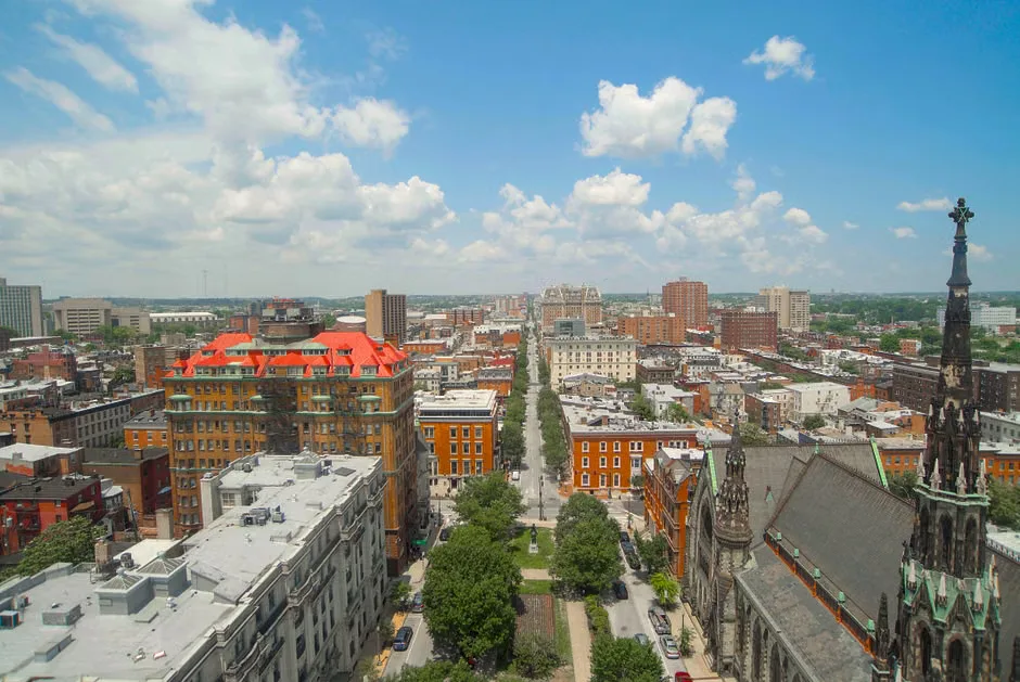 Downtown Baltimore street during extreme heat with people walking in strong sunshine
