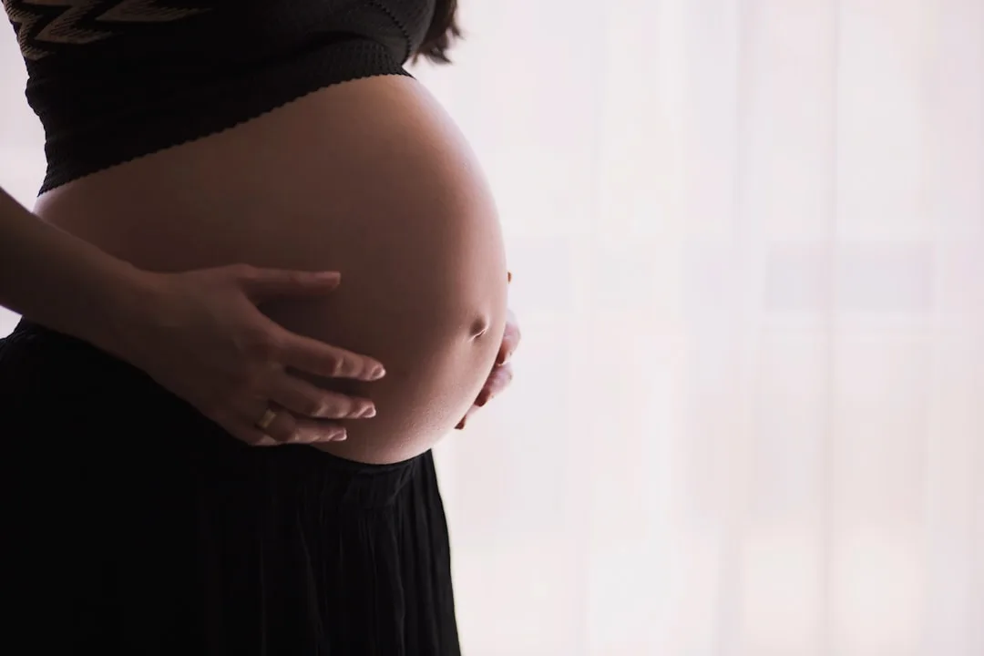 A pregnant patient discusses symptoms with a doctor in a medical exam room.